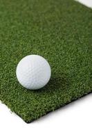 Golf Ball Resting on Section of Artificial Turf Grass On White Background photo