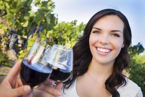 mujer joven disfrutando de una copa de vino en un viñedo con amigos foto