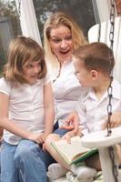 Young Boy Reads to His Mother and Sister photo