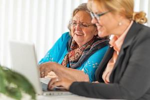 Woman Helping Senior Adult Lady on Laptop Computer photo