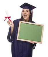 mujer graduada en toga y birrete con diploma, pizarra en blanco foto