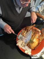 Senior Adult Man Cutting The Holiday Turkey photo