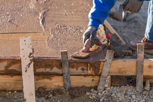 trabajador de la construcción alisando cemento húmedo con herramientas de paleta foto