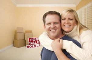 Couple in New House with Boxes and Sold Sale Sign photo