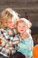 un dulce niño juega con su hermanita en un rancho rústico en el huerto de calabazas. foto