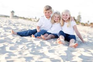 adorables hermanas y hermano divirtiéndose en la playa foto