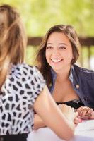 dos novias de raza mixta conversando en una mesa de patio al aire libre foto