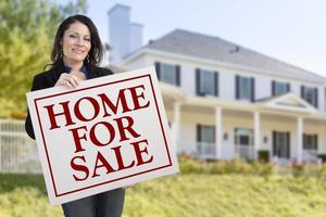 Woman Holding Home For Sale Sign in Front of House photo