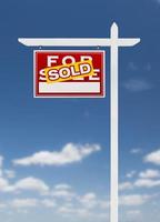 Left Facing Sold For Sale Real Estate Sign on a Blue Sky with Clouds. photo