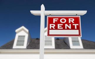 Right Facing For Rent Real Estate Sign In Front of House and Deep Blue Sky. photo