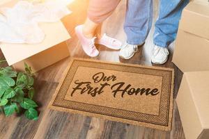 Man and Woman Unpacking Near Our First Home Welcome Mat, Moving Boxes and Plant photo