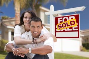 Hispanic Couple, New Home and Sold Real Estate Sign photo