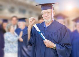 Proud Senior Adult Man In Cap and Gown At Outdoor Graduation Ceremony. photo