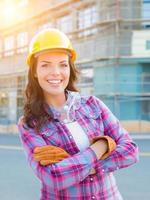 retrato de una joven trabajadora de la construcción con guantes, casco y gafas protectoras en el lugar de la construcción. foto