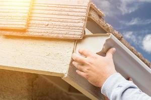 Worker Attaching Aluminum Rain Gutter to Fascia of House. photo