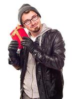 Warmly Dressed Young Man Holding Wrapped Gift To His Ear photo