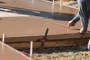 trabajador de la construcción encajando la línea en el cemento húmedo de la cubierta foto