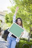 estudiante de raza mixta emocionada sosteniendo pizarra en blanco foto