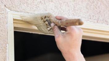 pintor profesional cortando con pincel para pintar el marco de la puerta de la casa. foto