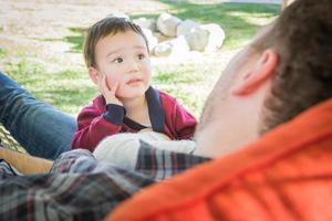 Mixed Race Boy Having Fun Outside While Parents Talk To Him From Hammock photo