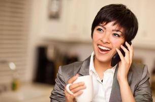 mujer multiétnica con café habla por teléfono celular foto