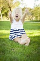 Cute Little Girl with Thumbs Up in the Grass photo