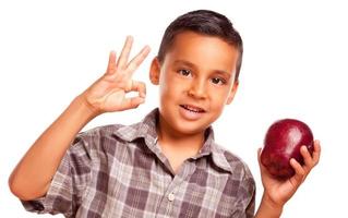 adorable niño hispano con manzana y signo de mano bien foto