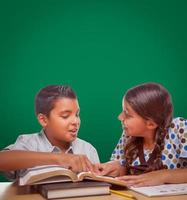 pizarra en blanco detrás de un niño y una niña hispanos divirtiéndose estudiando juntos foto