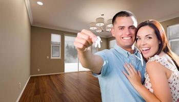 Young Military Couple with House Keys In Empty Room of New Home. photo