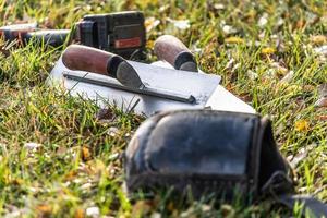 Cement Trowels And Tools On Grass At Construction Site photo