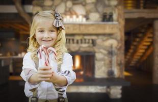 Cute Young Girl Holding Candy Canes in Rustic Cabin photo