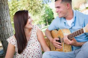 Young Adult Man Playing Guitar for His Girlfriend in the Park. photo