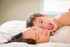 niño chino y caucásico de raza mixta acostado en su cama con su madre. foto