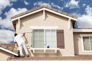 Professional House Painter Painting the Trim And Shutters of A Home. photo