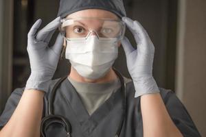 Female Doctor or Nurse Wearing Scrubs, Protective Face Mask and Goggles photo