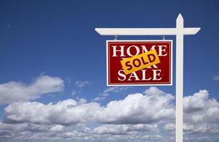 casa vendida roja en venta signo de bienes raíces sobre las nubes y el cielo foto
