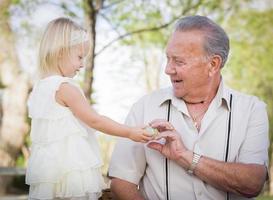 Cute Baby Girl Handing Easter Egg to Grandfather Outside photo