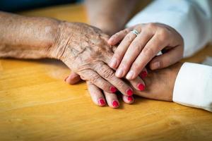 Younger Female Hands Holding Senior Adult Woman Hands photo