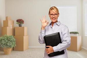 Woman with Okay Sign in Empty Room with Packed Moving Boxes photo