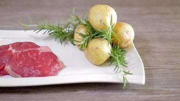 Delicious raw beaf steak isolated in a plate. Ready to be cooked or grilled. Food for barbecue. Ideal for home kitchen or restaurant. Sliding shot.