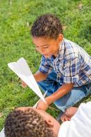 Happy African American Father and Mixed Race Son Playing with Paper Airplanes in the Park photo