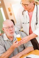 Doctor or Nurse Explaining Prescription Medicine to Attentive Senior Man photo