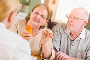 Doctor or Nurse Explaining Prescription Medicine to Senior Adult Couple photo