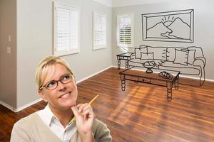 mujer con lápiz en la habitación vacía de la casa nueva con sofá y mesa dibujando en la pared foto