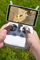 Hands Holding Drone Quadcopter Controller With Construction House Framing on Screen photo