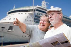 Happy Senior Adult Couple Tourists with Brochure Next To Passenger Cruise Ship. photo