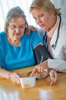 Senior Adult Woman Learning From Female Doctor to Use Blood Pressure Machine photo