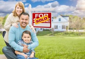 Mixed Race Family In Front of House and Sold For Sale Real Estate Sign photo