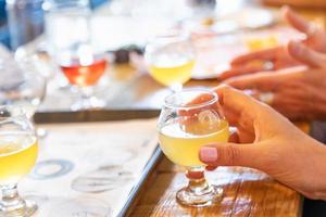 Female Hand Holding Glass of Micro Brew Beer At Bar photo