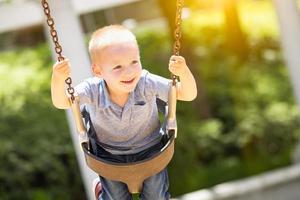 Happy Young Boy Having Fun On The Swings At The Playground photo